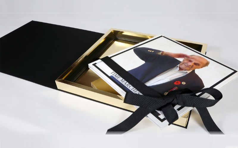 Hardcover book on top of gold trimmed box with ribbon.